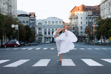 Girl dancer on the road in the city at dawn