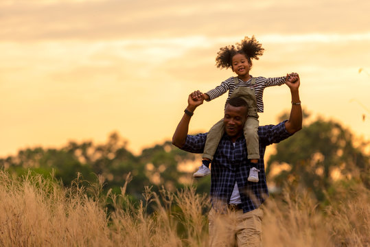Happy African family father and child daughter travel and running on meadow nature on silhouette lights sunset.  Travel and Family Concept