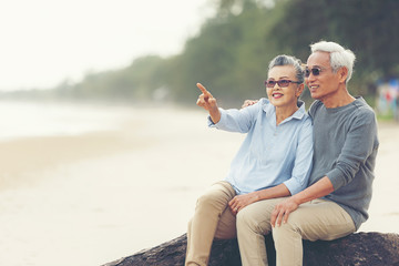 Asian Lifestyle senior couple hug and pointing on the beach happy in love romantic and relax time.  People tourism elderly family travel leisure and activity after retirement in vacations and summer
