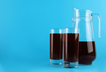 Delicious homemade kvass in glasses and jug on light blue background. Space for text
