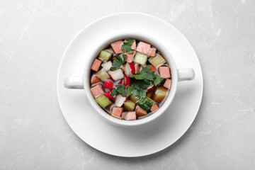 Delicious cold okroshka with kvass on light grey table, top view. Traditional Russian summer soup