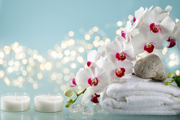 Winter spa decorations with orchid, 2 candles and towel on blue background