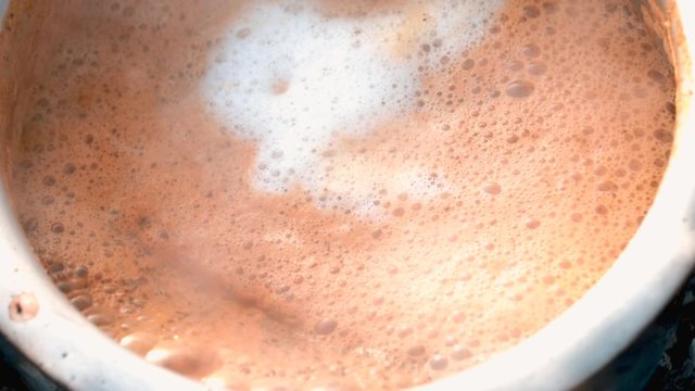 Indian style Hot Milk tea/chai, Selective Focus is used.Masala tea in iron pan with fire background,stone stove in Kolayat cattle fire Indian style Hot Milk tea/chai,making chai over a fire outside
