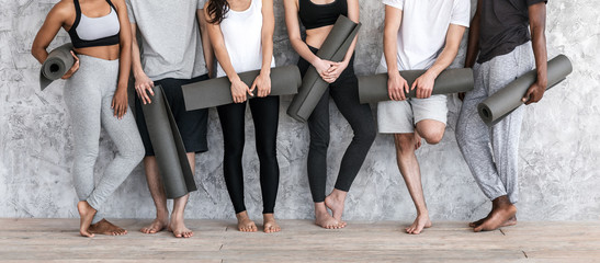 Diverse People In Sportswear With Yoga Mats In Hands Posing Near Wall