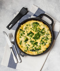 Omelette with green vegetables, broccoli and green pea in a frying pan.