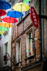 Colorful decoration in the streets with umbrellas and brick wall. Traslation "Tabac" mean : "Tobacco"