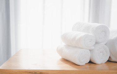 Obraz na płótnie Canvas Clean white towels fold on wood table with blurred white bathroom background