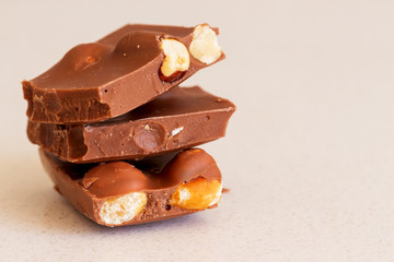 Stack of milk chocolate with nuts on white background. Copy space for text. Close-up photo of sweets, confection and candies, chocolate texture