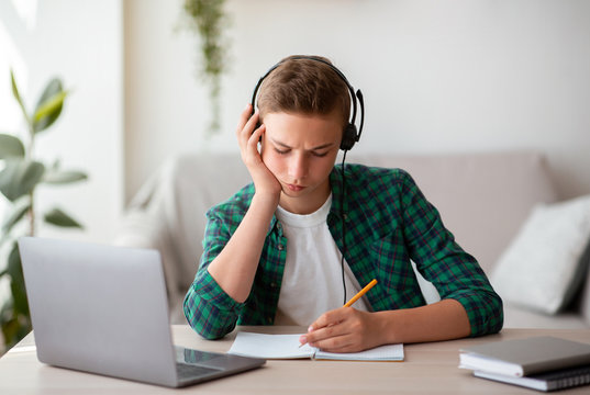 Serious teen guy studying online from home