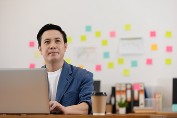Asian senior business man in casual working with laptop in modern office or co-working space,Business Startup Concept