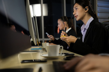 Group of Young call center staff talking and provide services to customers via headphones and microphone cable. Professionals with speech, service mind and information recording skills. Night mode.