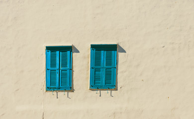 Windows with blue shutters on the white lime wall