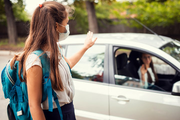 Mother in car, dropping off her daughter to the school and wishing her a good day. Back to school,...