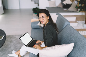Portrait of prosperous caucasian female in eyewear for vision correction enjoying wireless...