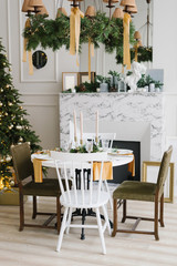 Christmas atmosphere and comfort in the living room. Festive table near the marble fireplace and Christmas tree