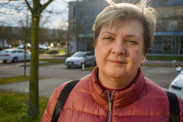 A Mature woman in a red jacket walks through the streets