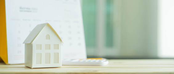 close up on home model with calculator and calendar on blue  background with space for money management ,home loan and personal financial concept