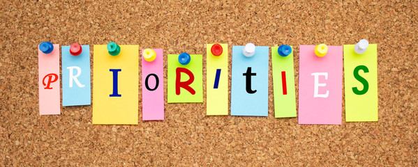 Multicolor notes with letters pinned on a cork notice board.