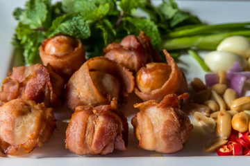 Mini sausages wrapped in smoked bacon in dish. Grilled sausages wrapped in bacon fat of delicious. smoked pork sausage roll wrapped by roasted bacon.