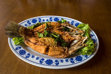 Fried sea bass fish in white plate with spicy and sweet sauce in Thai style .  crispy Thai style deep fried whole sea bass fish served with spicy mango sauce. crispy deep fried sea bass 