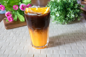 Two layer of combination between orange juice and Black Coffee. Orange and coffee cocktail on the wooden background. Ice coffee mixed with orange juice. Black Coffee Tonic 