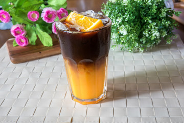 Two layer of combination between orange juice and Black Coffee. Orange and coffee cocktail on the wooden background. Ice coffee mixed with orange juice. Black Coffee Tonic 