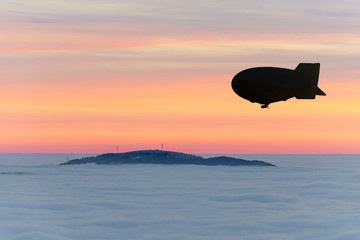 Blimp Flying over Mountain Peak with Cloudscape in Dusk in Switzerland.