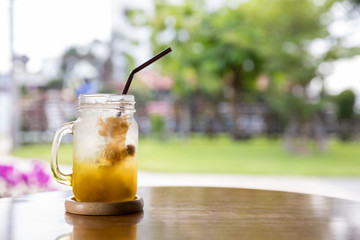 Italian Soda Cold Beverage and Plum  Fruit on top in cafe. Plum drink (cocktail) with mint and ice in glass. glass of Plum Italian soda on a wooden saucer in cafe with green nature background 