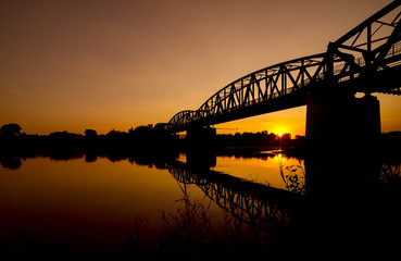 Railway Bridge near Barby at sunset reflecting in the river Elbe.