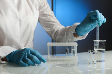 scientist's hands in gloves are conducting chemical experiments in lab close up