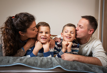 Family portrait. Parents with their children lying down on bed and making fun. Moving into a new home.
