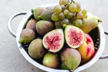 Composition with ripe fresh figs, grape,pear and nectarines in metal bowl on grey background. Healthy sweet dessert, no calories. Close up, top view.