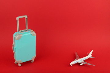 travel concept. toy airplane and a blue suitcase on a red background with copy space