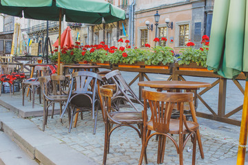 Tables and chairs in empty  restaurant.
Open outdoors cafe with chairs and tables.