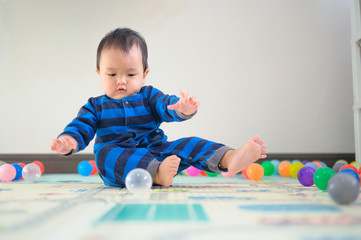 Fototapeta na wymiar Kid playing with ball on soft carpet in children room