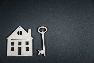 Real estate concept. Small toy wooden house with keys on grey background