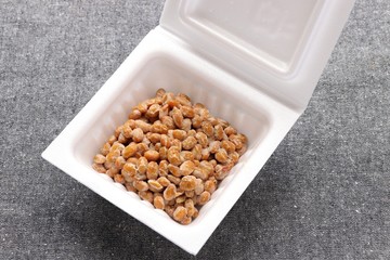 Natto, fermented soybeans in styrofoam container on gray background