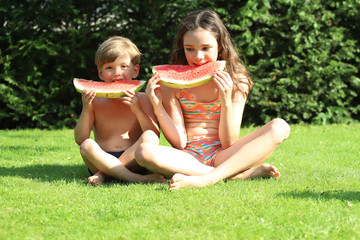 Kinder essen eine Wassermelone im Garten