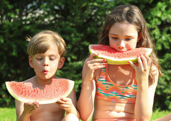 Kinder essen eine Wassermelone im Garten
