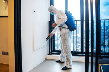 Asian man in protection germ suit or PPE suit  to protect against COVID-19 using nebulizers, Face shield, Mask, and Alcohol gel for cleaning place and use chemicals disinfecting in balcony, quarantine