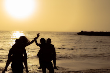 Fototapeta premium People silhouettes near the sea at sunset. Young people having fun on summer vacation. Travel, party and friendship concept. Image