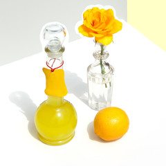 Bottle of Italian limoncello, lemon and yellow rose. Modern minimalistic still life on a geometric...