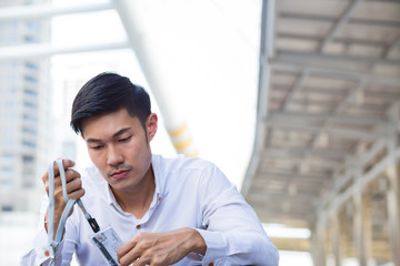 Young businessman who depresss after unemployed . He sit on the floor after fired .  A man sit on the floor in the city. He watch at the id card.