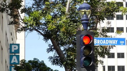 Broadway street name, odonym sign and traffic light on pillar in USA. Road intersection in downtown of city. Crossroad in urban central business district. Nameplate banner with title of main avenue.