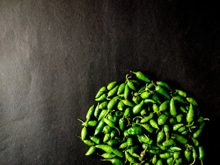Many small green chillies isolated on black background. Copy space.