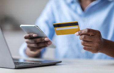 Online Payment. Unrecognizable black female using smartphone and credit card in office