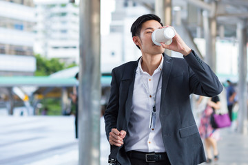 Young businessman having coffee while using smart phone.