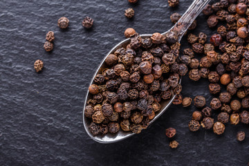 aromatic black pepper on a dark stone background
