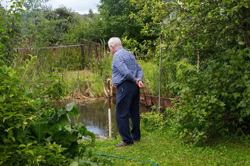 An elderly man on the edge of the pond