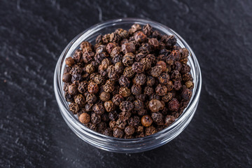 aromatic black pepper on a dark stone background